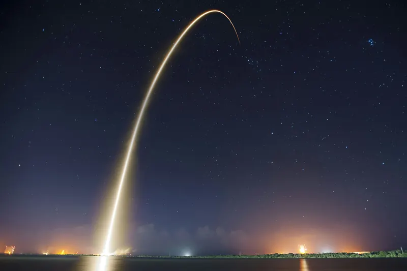 La trajectoire lumineuse d'une fusée qui s'élève dans le ciel de nuit