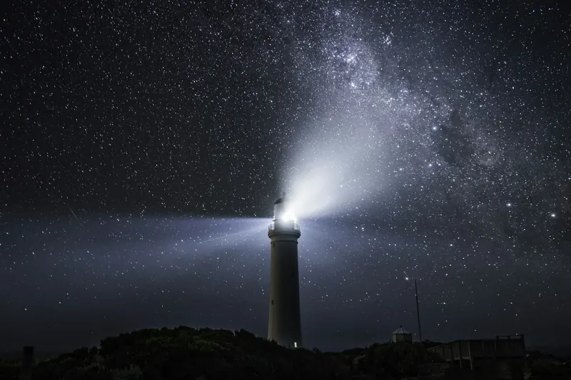 Un phare éclaire la nuit étoilée