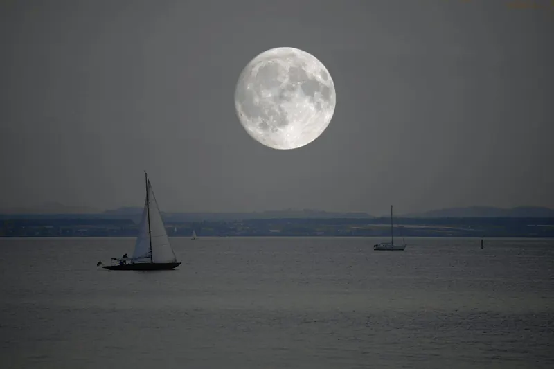 Des voiliers sur une mer calme, sous la pleine lune