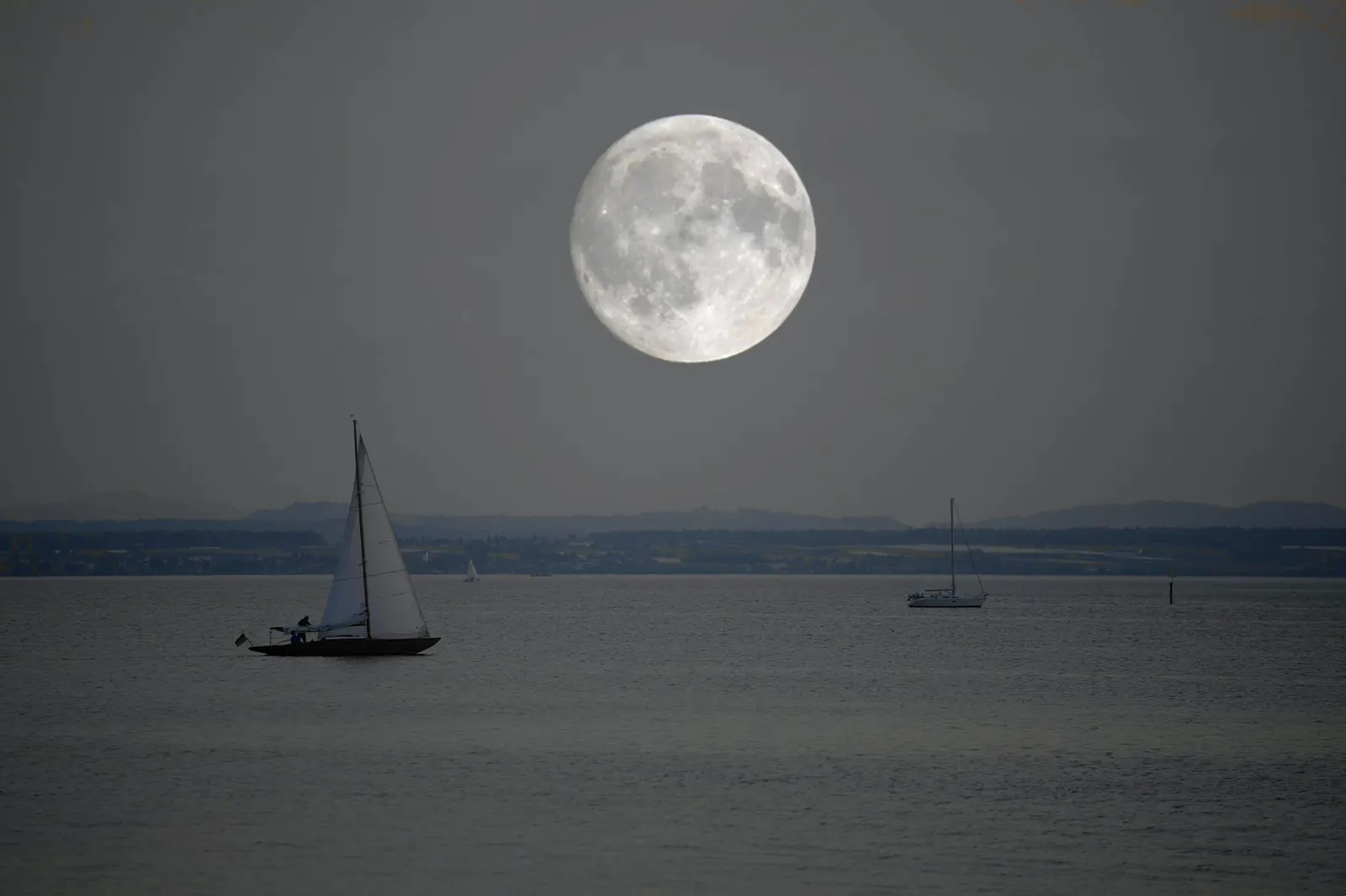 Des voiliers sur une mer sombre, sous la pleine lune